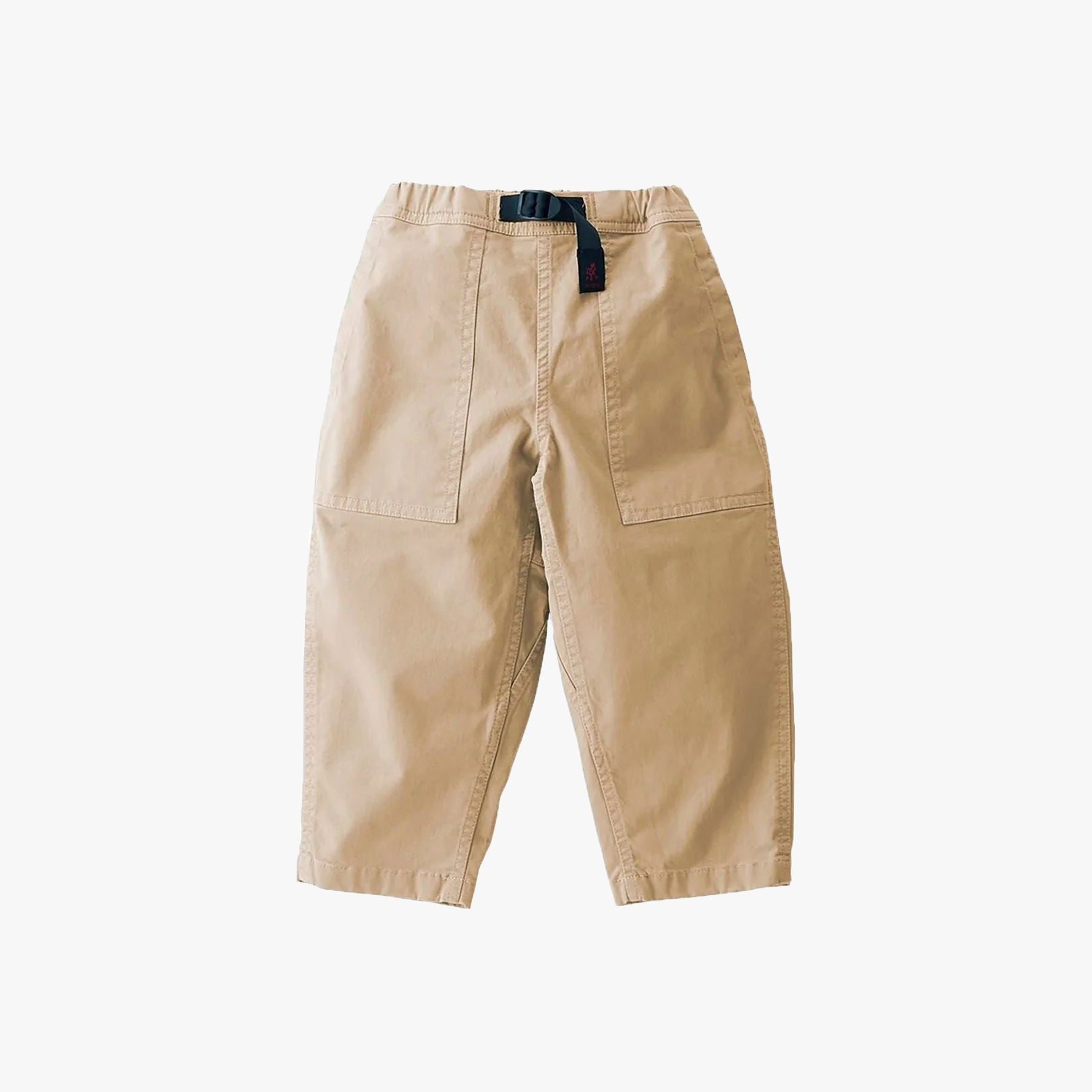 A pair of Gramicci K Loose Tapered Pant, Chino in beige stretch twill with large front pockets and a black adjustable belt, laid flat on a white background.