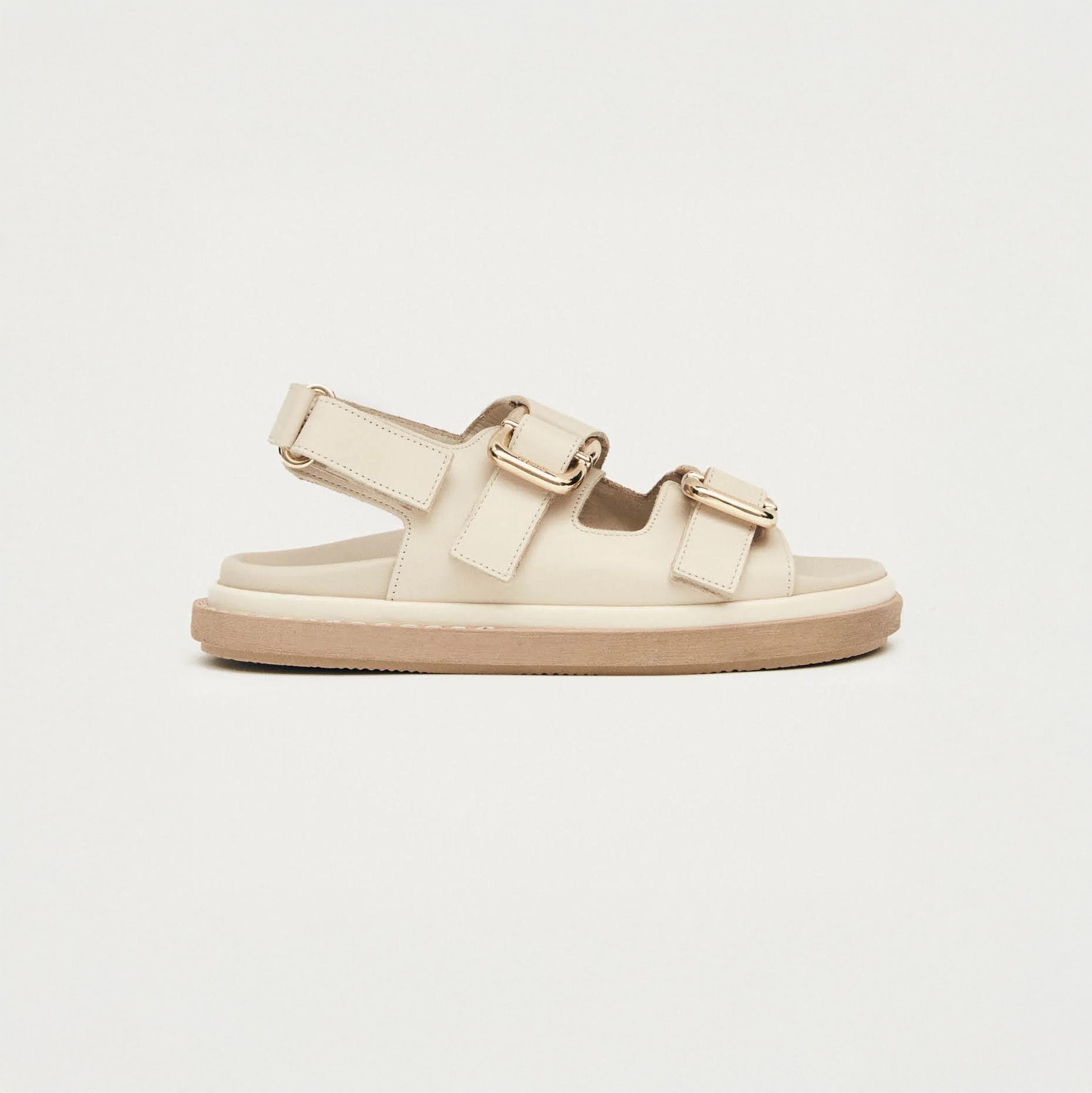 The Alohas Harper Sandal in cream features two adjustable buckle straps and a chunky sole, displayed in side profile against a plain white background.