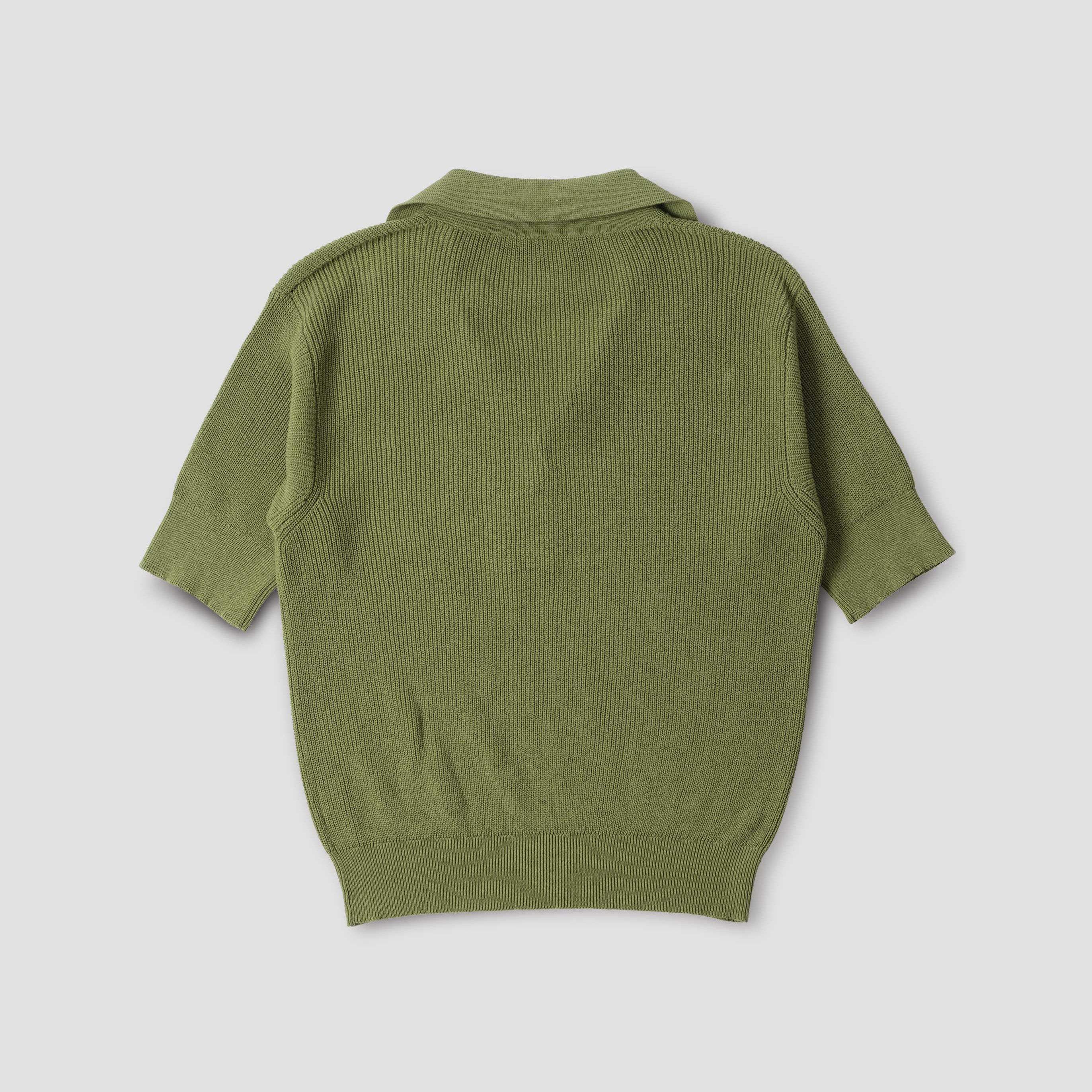 The W Single Button Polo by Margaret Howell is an olive green, short-sleeved knit sweater in a half cardigan stitch with ribbed cuffs and hem, shown from the back against a plain white background.