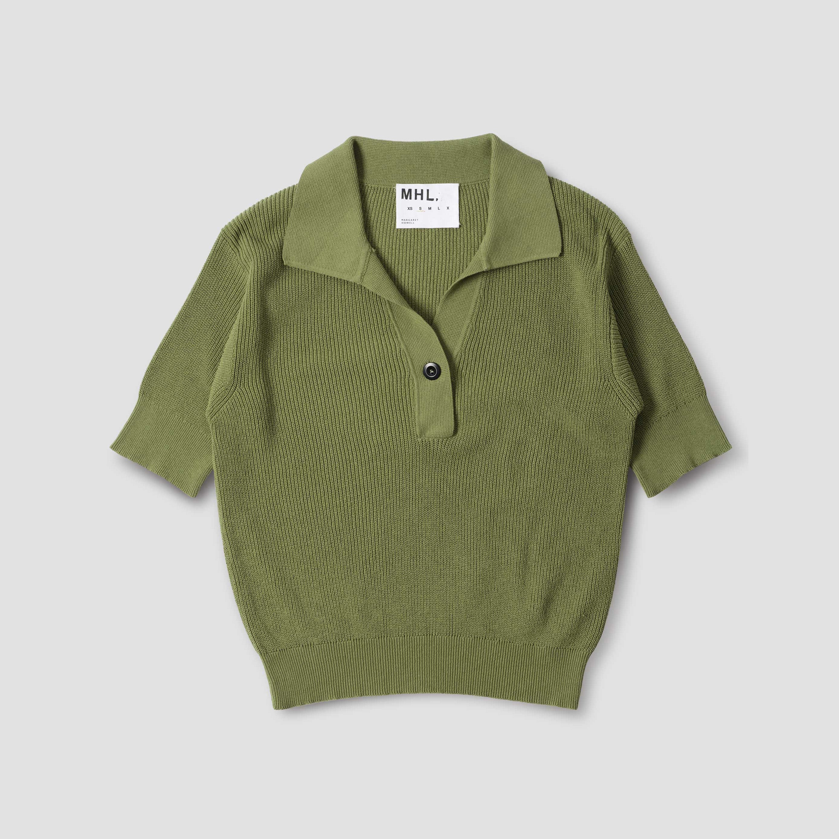 The W Single Button Polo by Margaret Howell is an olive green cotton knit shirt with short sleeves, a collar, a single front button, relaxed fit, and features a visible MHL label inside the neckline.