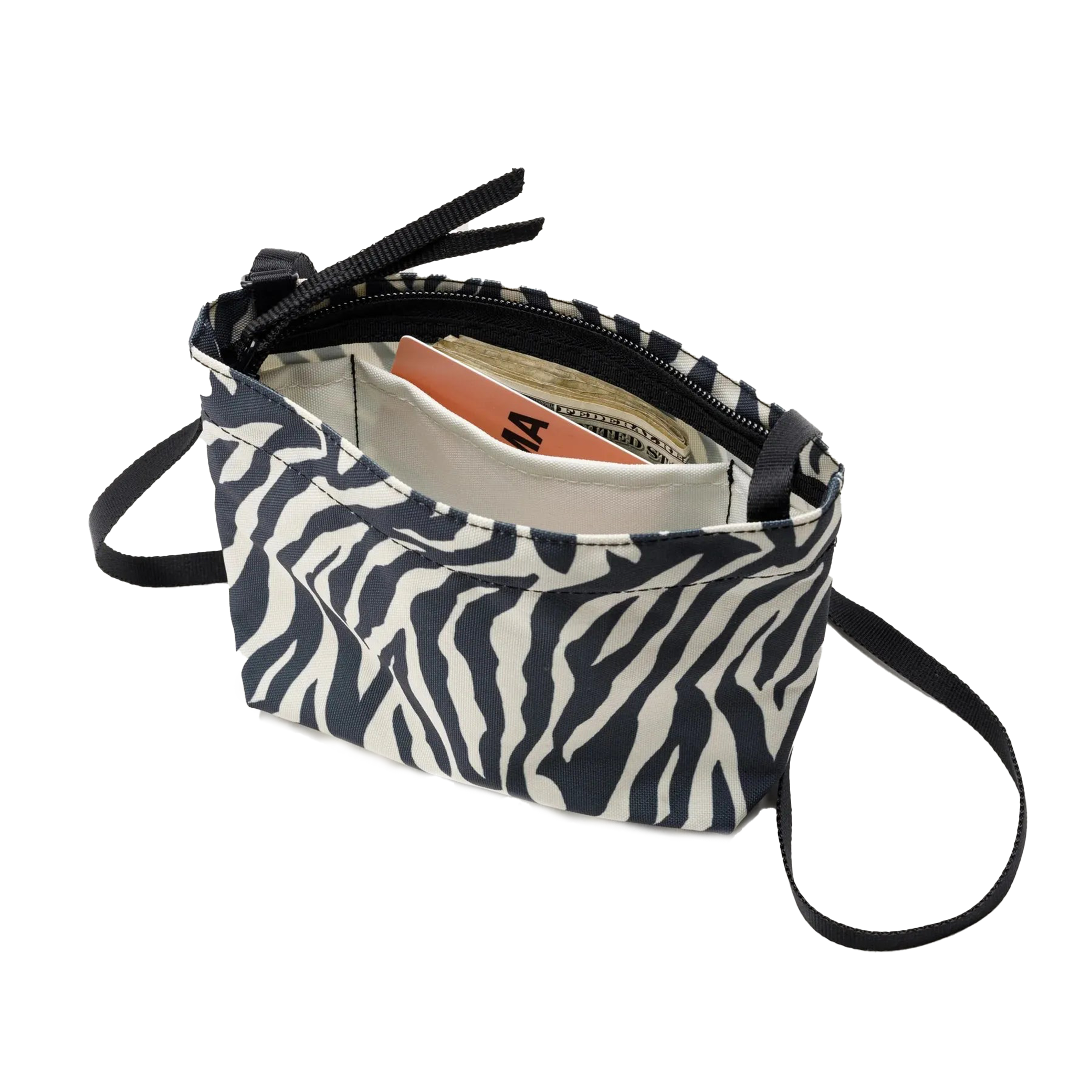 A Zipper Pouch Mini by Bags in Progress, designed with a zebra print and made from recycled polyester, is open to reveal a book, cash, and an envelope inside.
