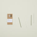 A box of Hawkins New York Essential Glass Straws - Set of 6 featuring clear and green straws with a cleaning brush is beautifully displayed on the left against a light background.