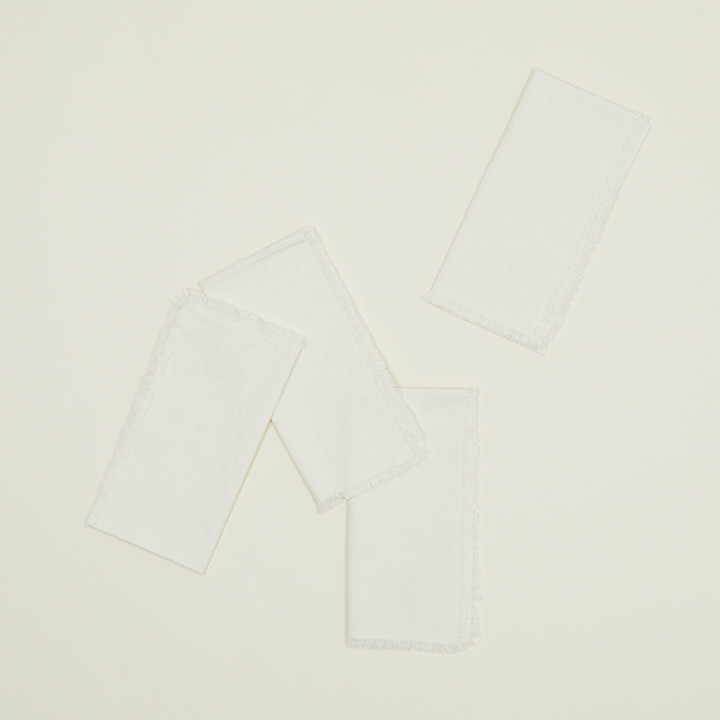 The Hawkins New York Essential Dinner Napkins (Set of 4) feature rectangular white cloth with frayed edges—ideal for easy living and timeless home basics.
