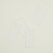 The Hawkins New York Essential Dinner Napkins (Set of 4) feature rectangular white cloth with frayed edges—ideal for easy living and timeless home basics.