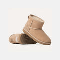 Tan suede Ugg K Classic Mini II boots with plush lining and thick, cushioned outsoles. One boot is upright, highlighting the signature branded heel tag, while the other lies on its side.
