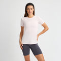 A person in a Jacquard Short Sleeve Tee by Rohnisch, made of breathable, recycled polyester, and dark shorts stands confidently with one hand on their hip against a plain background.