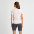 A woman with long hair, facing away, wears a Rohnisch Jacquard Short Sleeve Tee in pale pink made from breathable, recycled polyester paired with dark gray shorts against a white background.