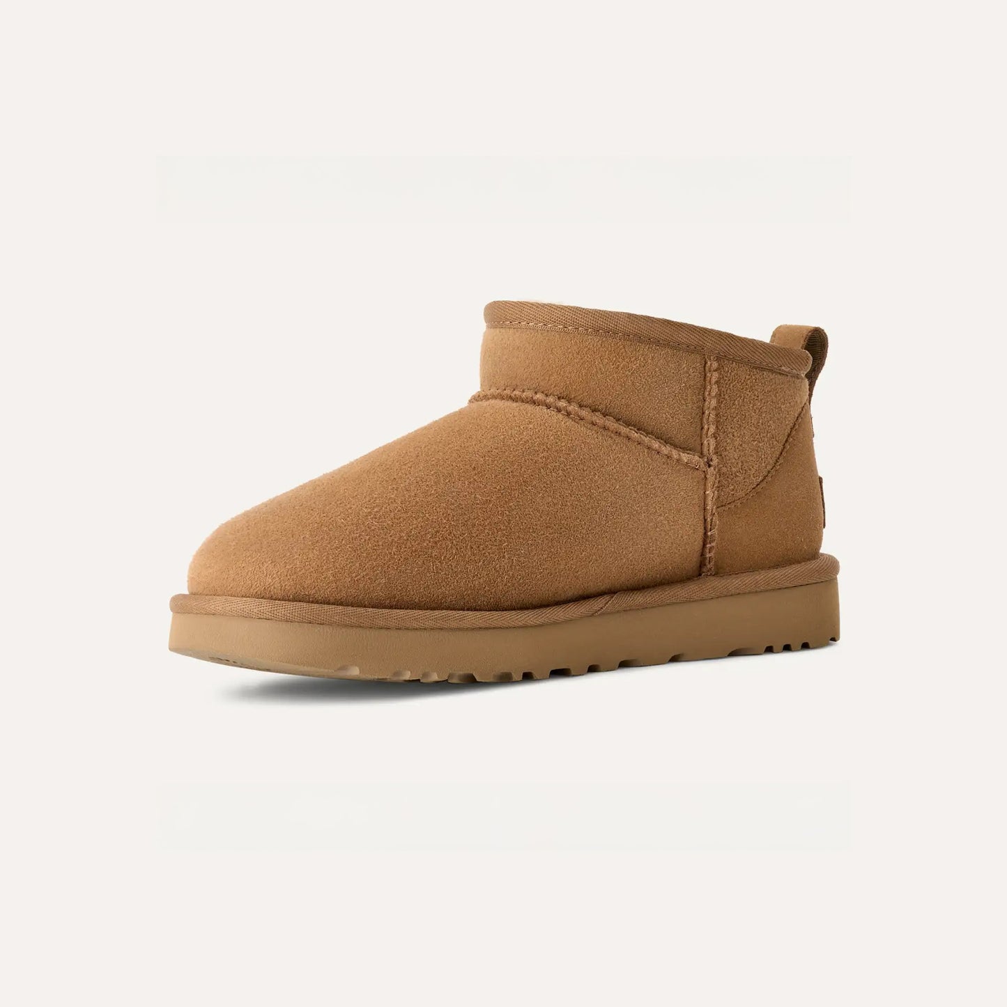 The Ugg W Classic Ultra Mini is a single tan suede ankle boot with an ultra-lightweight flat sole and a back pull tab, displayed against a plain background.