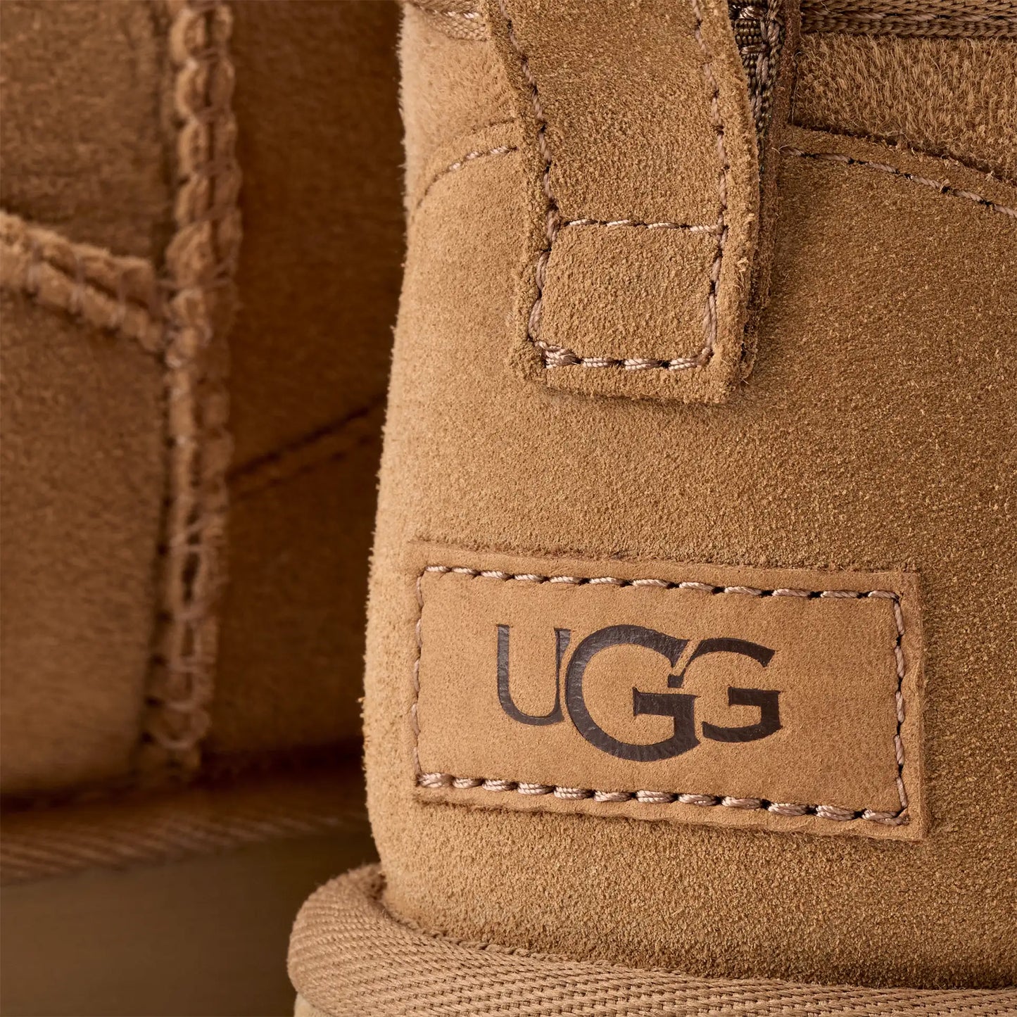 A close-up of the W Classic Ultra Mini Ugg boots shows the iconic logo stitched onto the suede exterior with an ultra-lightweight sole.