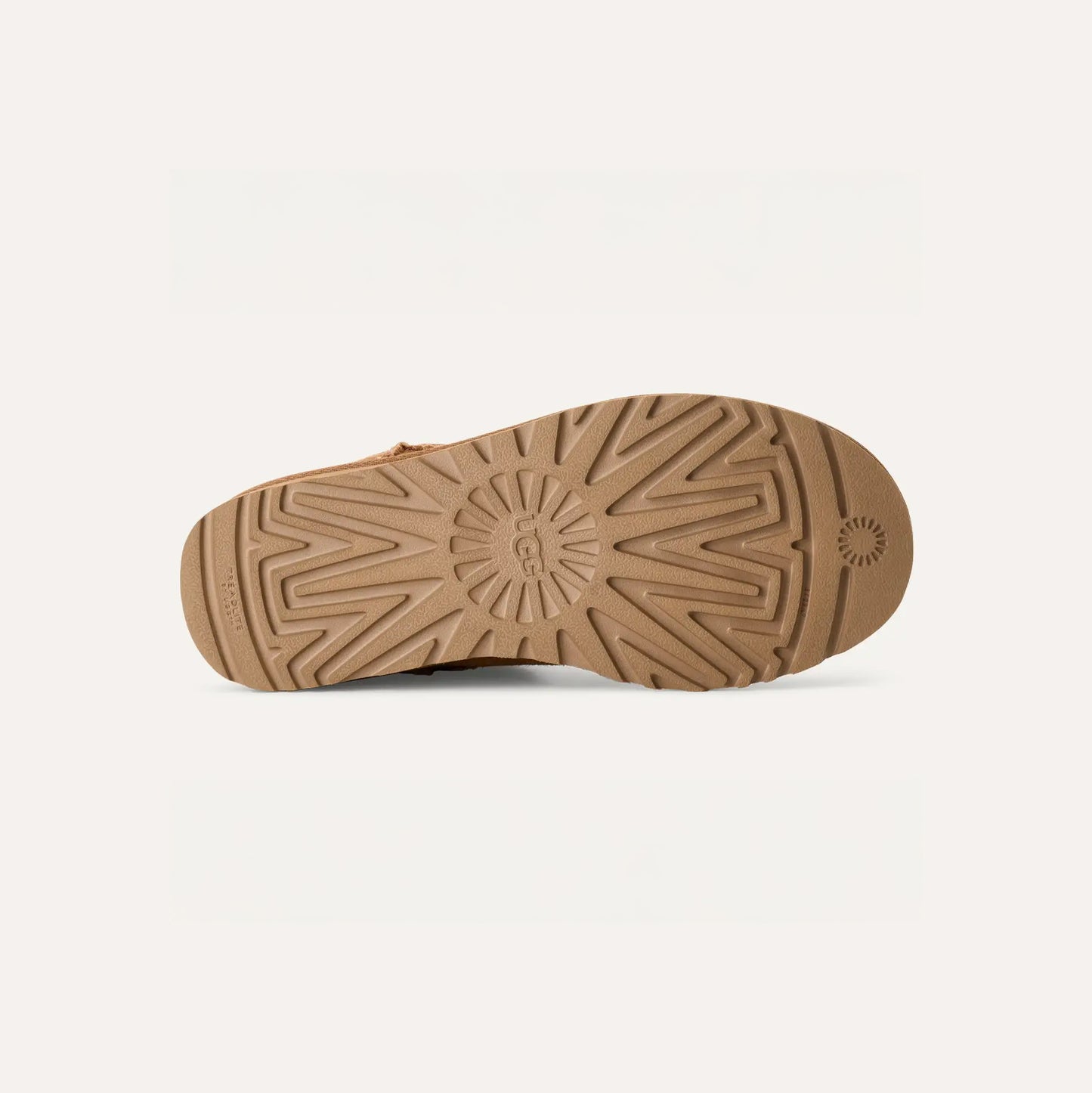 The textured brown sole of the UGG W Classic Ultra Mini features a circular logo near the heel, along with lines and zigzag patterns for added grip. Known for its ultra-lightweight design, it incorporates premium sheepskin comfort.