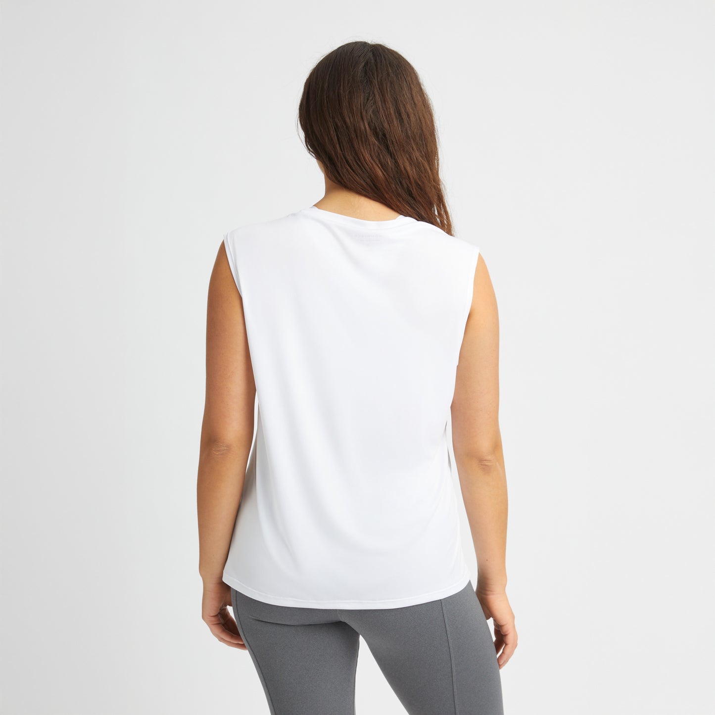 A person with long hair stands against a white background, wearing Rohnisch's breathable Team Logo Singlet and gray leggings.