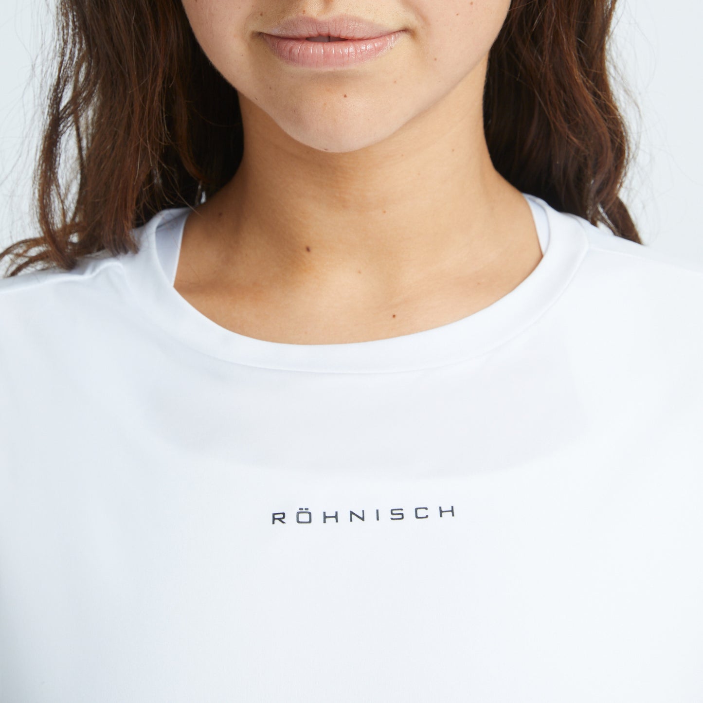 Close-up of a person wearing a breathable white Rohnisch Team Logo Singlet, with long brown hair partially visible.