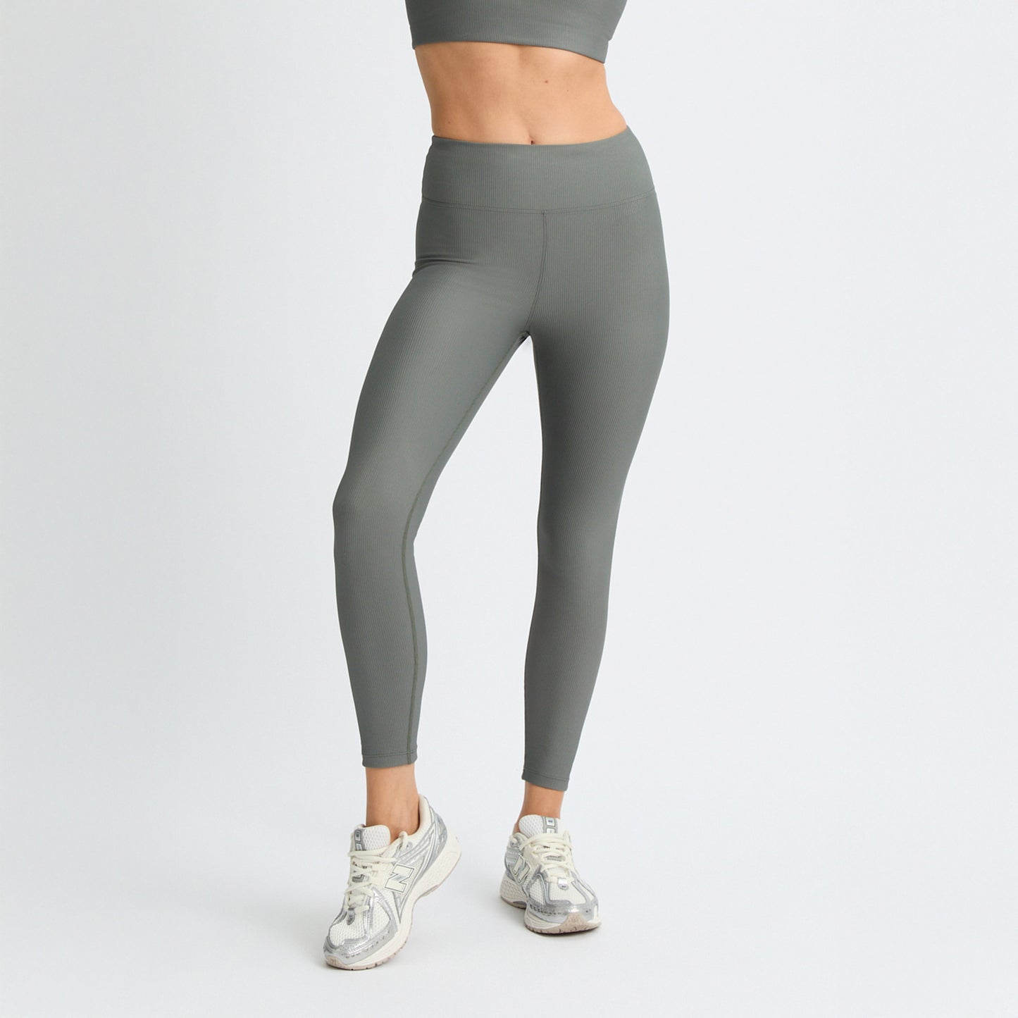 A person in Rohnisch Ribbed Regular High Waist Tights and sneakers stands against a white backdrop, exuding style and comfort.