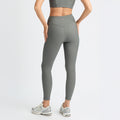 A person in Rohnisch Ribbed Regular High Waist Tights and a matching sports top stands with hands on hips, facing away. They wear sneakers, and the activewear is made from recycled polyester for an eco-friendly touch.