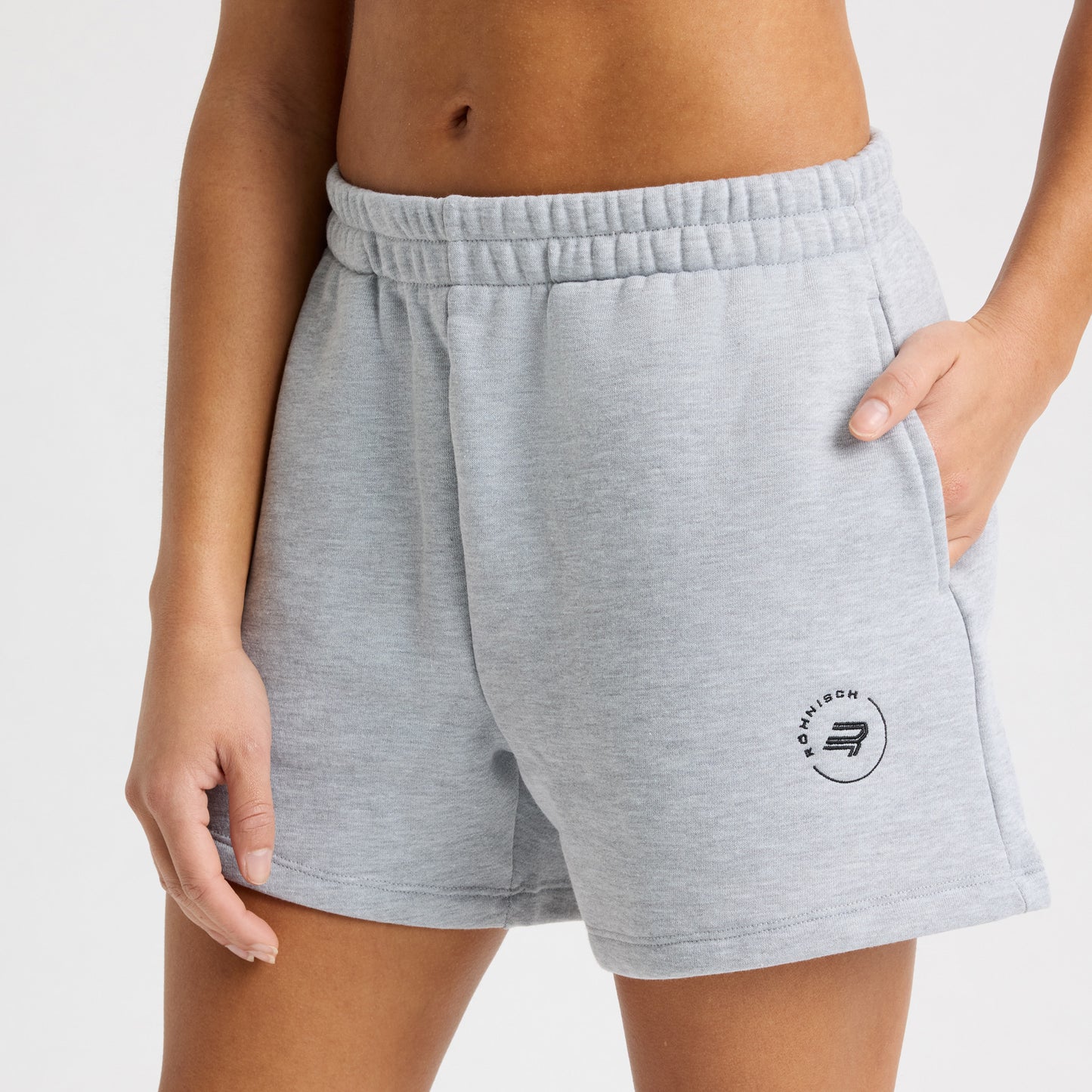 Someone is wearing Rohnisch's Soft Sweatshort in gray Terry fabric with a subtle logo print on the thigh, against a plain background.