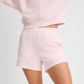 Someone is wearing Rohnisch Soft Sweatshorts and a matching sweatshirt in light pink, made from plush Terry fabric, shown from shoulders down against a plain background.