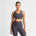 A person confidently poses against a plain white background wearing a Ribbed Sportsbra by Rohnisch, part of their dark athletic outfit.
