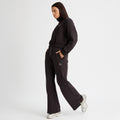 Someone wearing Rohnisch's Soft Sweat Wide Pants in black and silver sneakers stands in profile with hands in pockets against a plain white background.