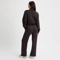 A woman in a black tracksuit and sneakers stands against a white background. She's wearing Rohnisch's Soft Sweat Wide Pants, combining style and comfort effortlessly.