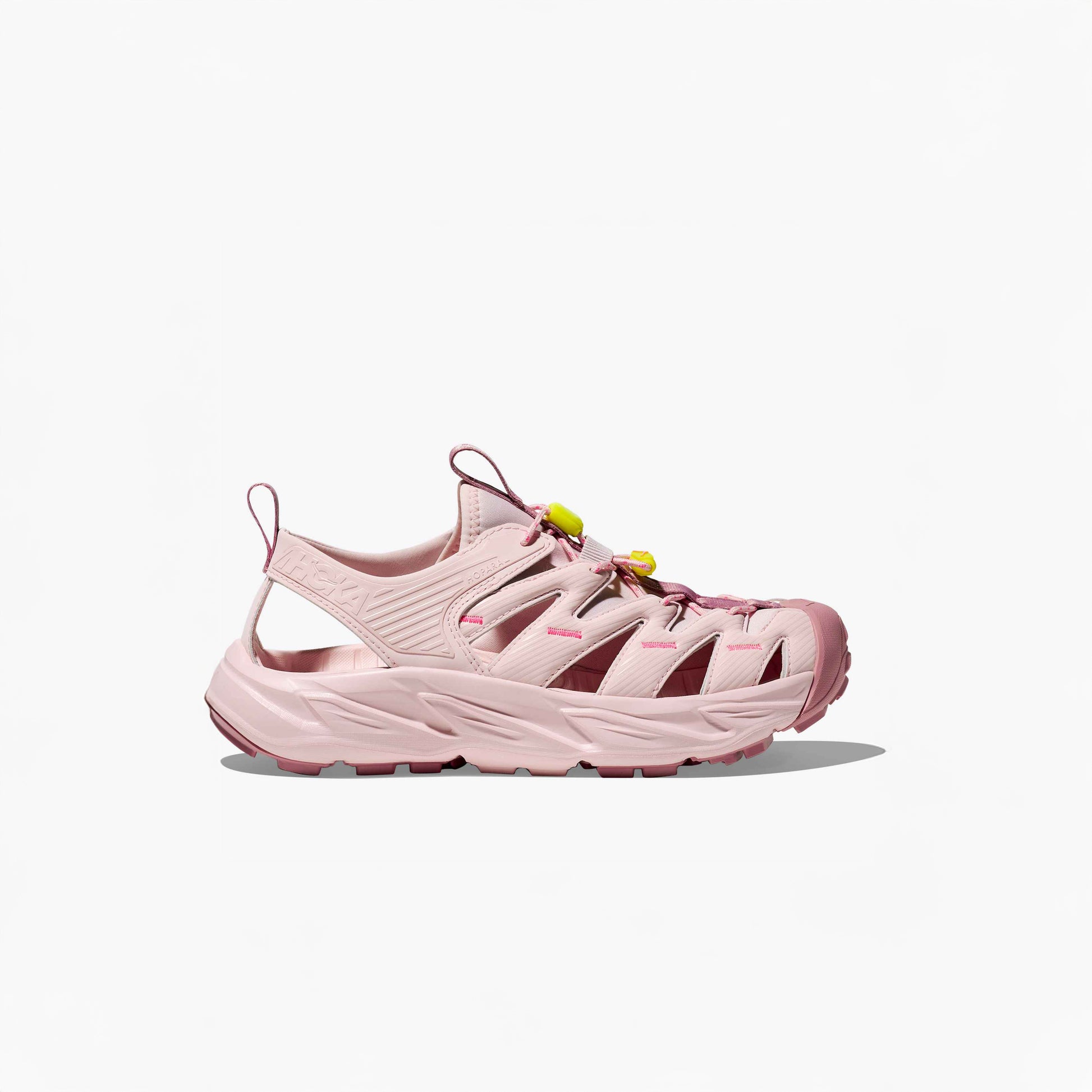 The Hoka U Hopara sandal in Rose Tea/Neon Rose features cut-out sides, a thick textured sole, and yellow Quick Lace toggle laces, shown on a plain white background.