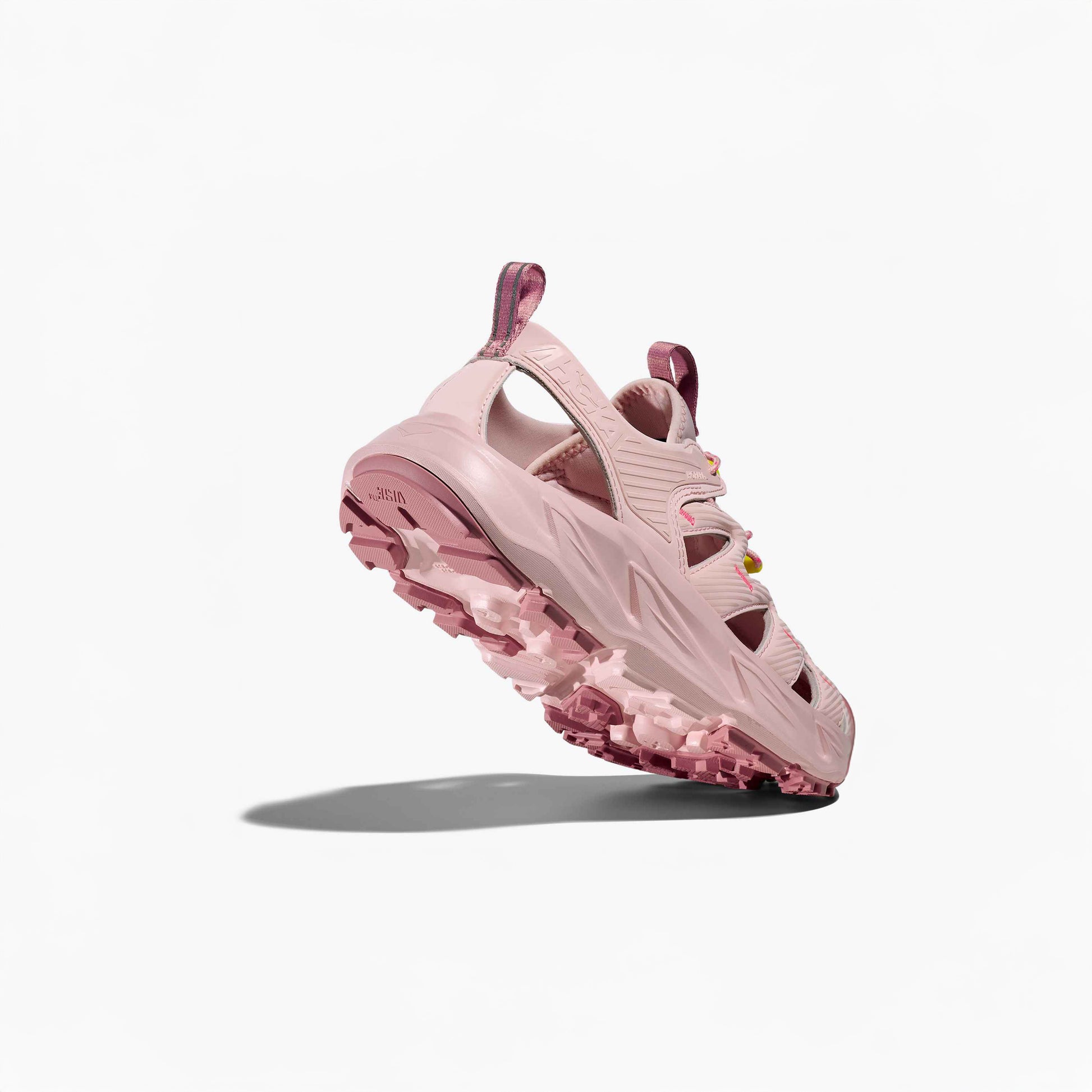 The Hoka U Hopara in Rose Tea/Neon Rose is a pink sneaker inspired by hiking sandals, featuring cut-out details and a rugged textured sole. It’s displayed against a plain white background, slightly elevated with a shadow beneath.