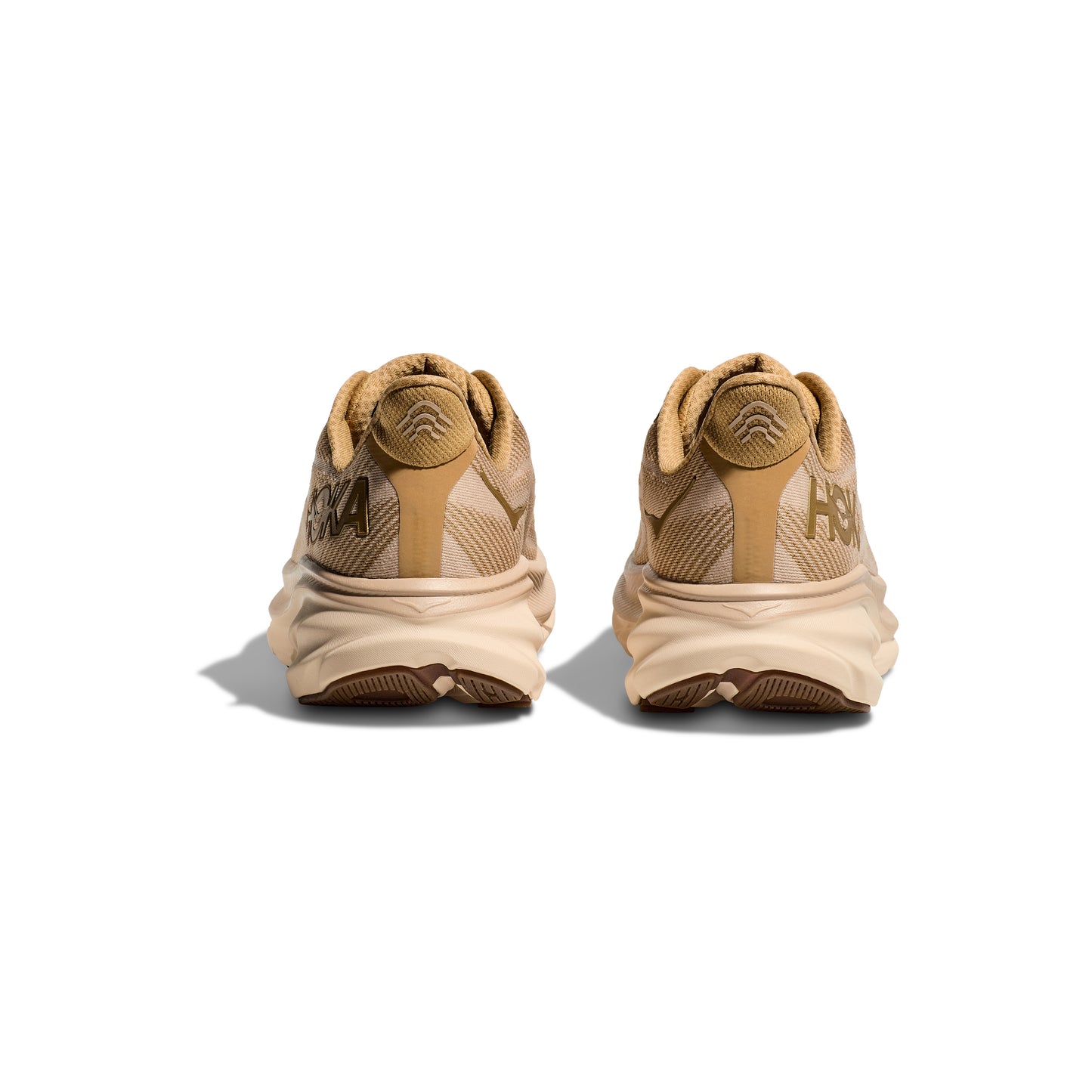 Rear view of a pair of Hoka M Clifton 9 running shoes in Wheat/Shifting Sand, featuring thick beige cushion soles for a responsive toe-off, set against a white background.