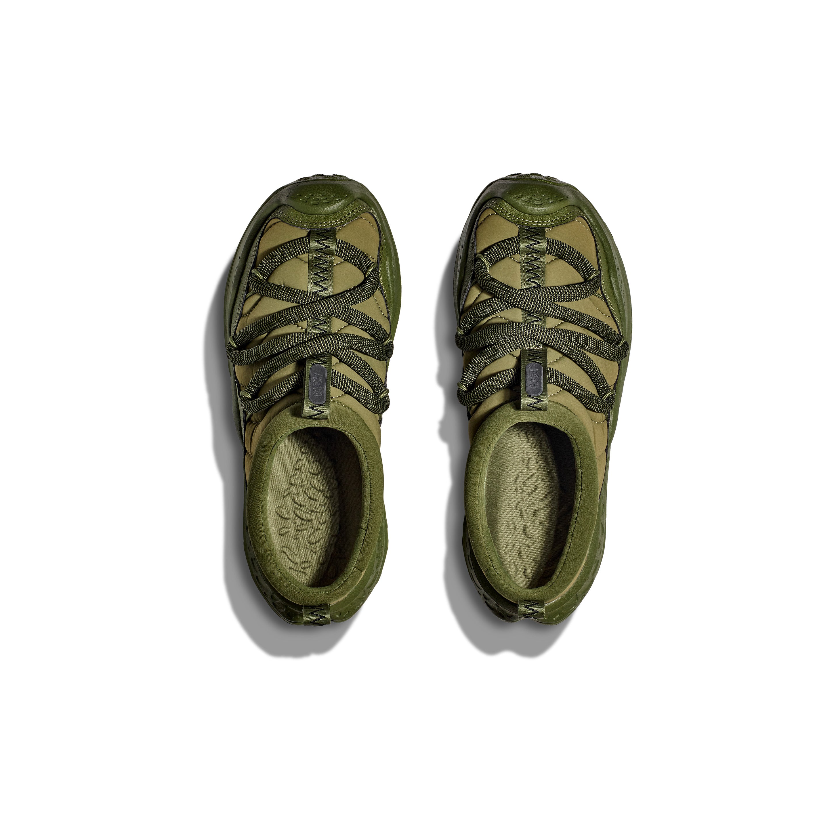 The Hoka U Ora Primo in green features crisscrossed laces and offers slip-on comfort for easy recovery after intense workouts, pictured from above on a white background.