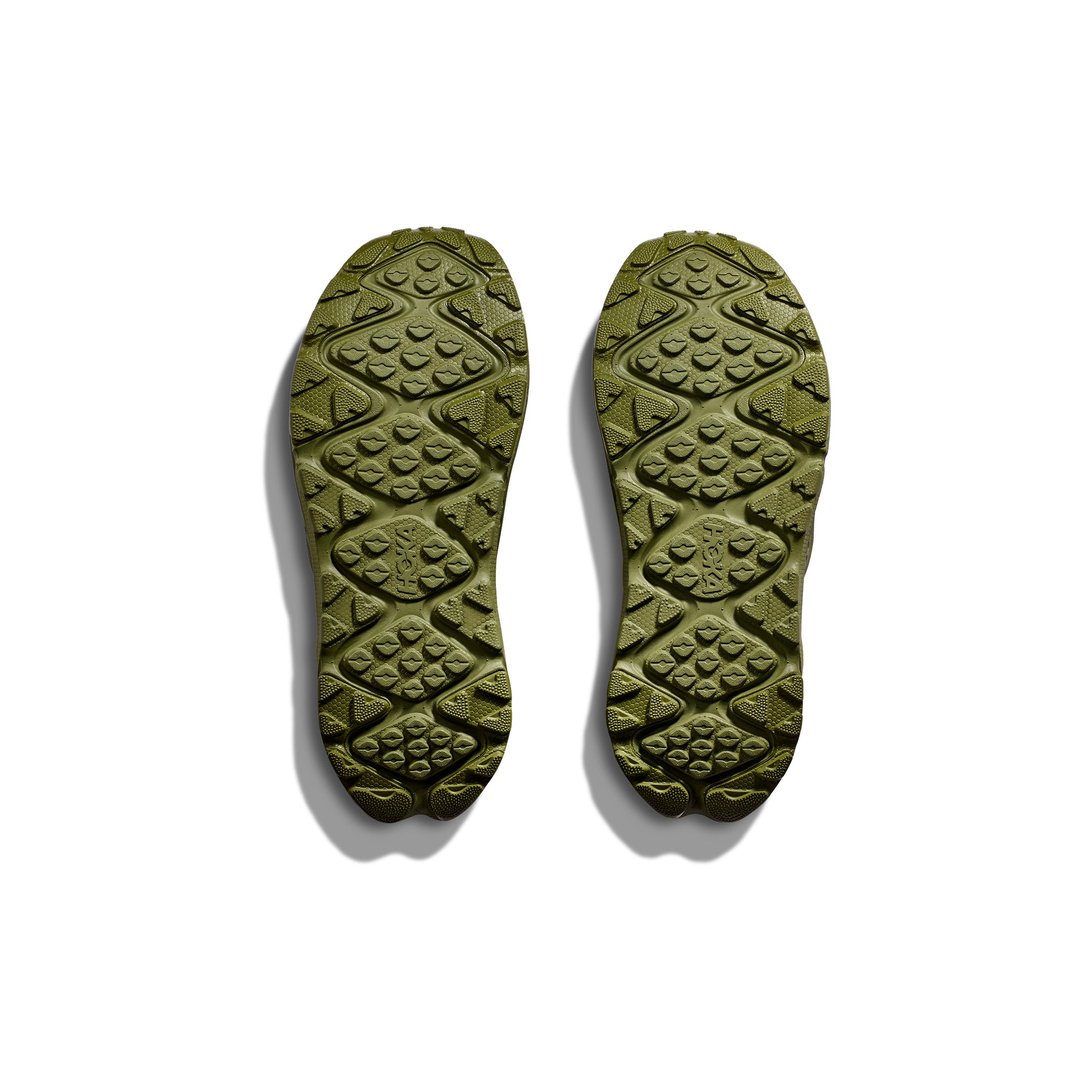 Two green U Ora Primo shoe soles by Hoka feature textured patterns for recovery and comfort. They are displayed from the bottom against a white background.