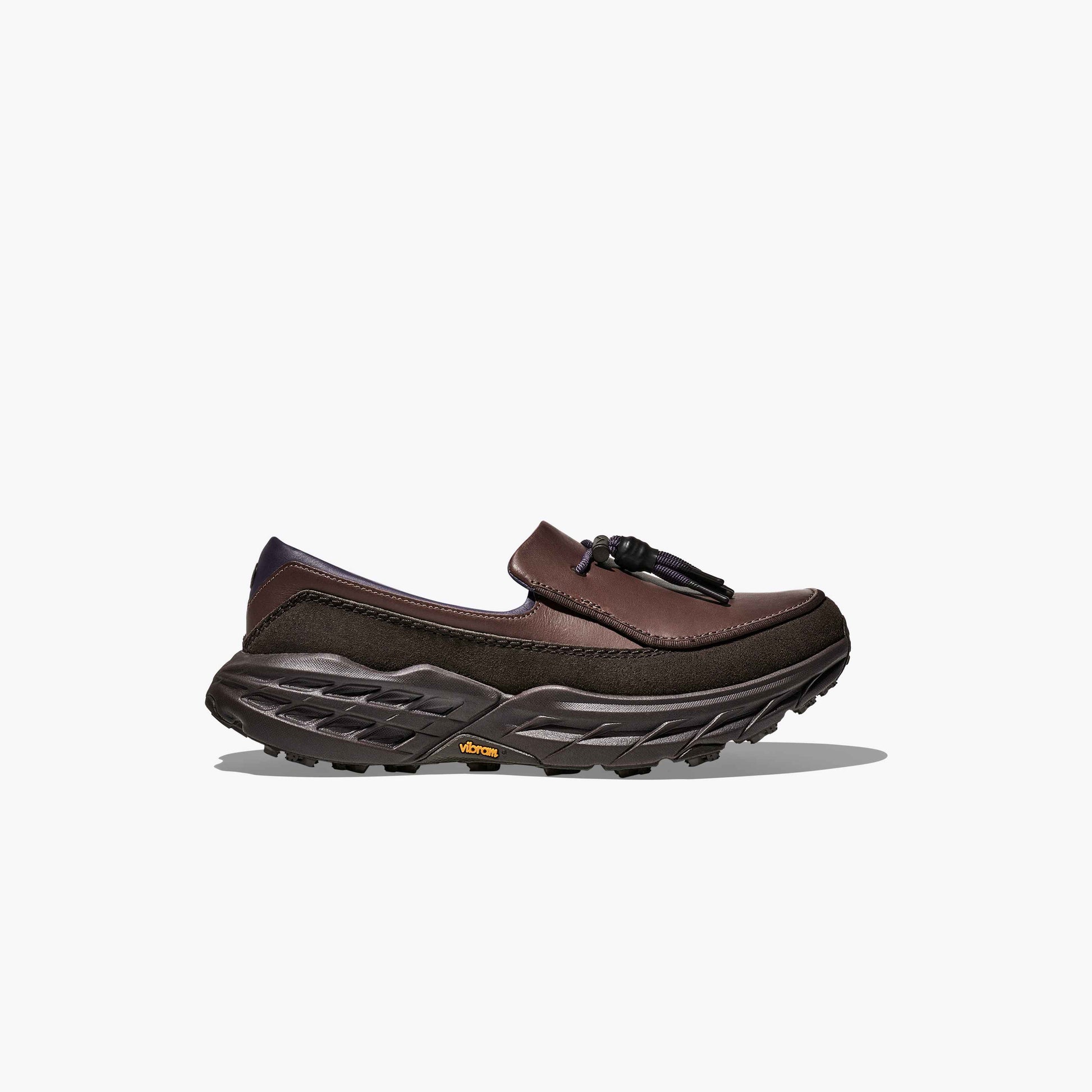 The Hoka U Speed Loafer features brown leather and suede, a chunky black treaded sole, and tassel detail, shown in profile against a plain white background.