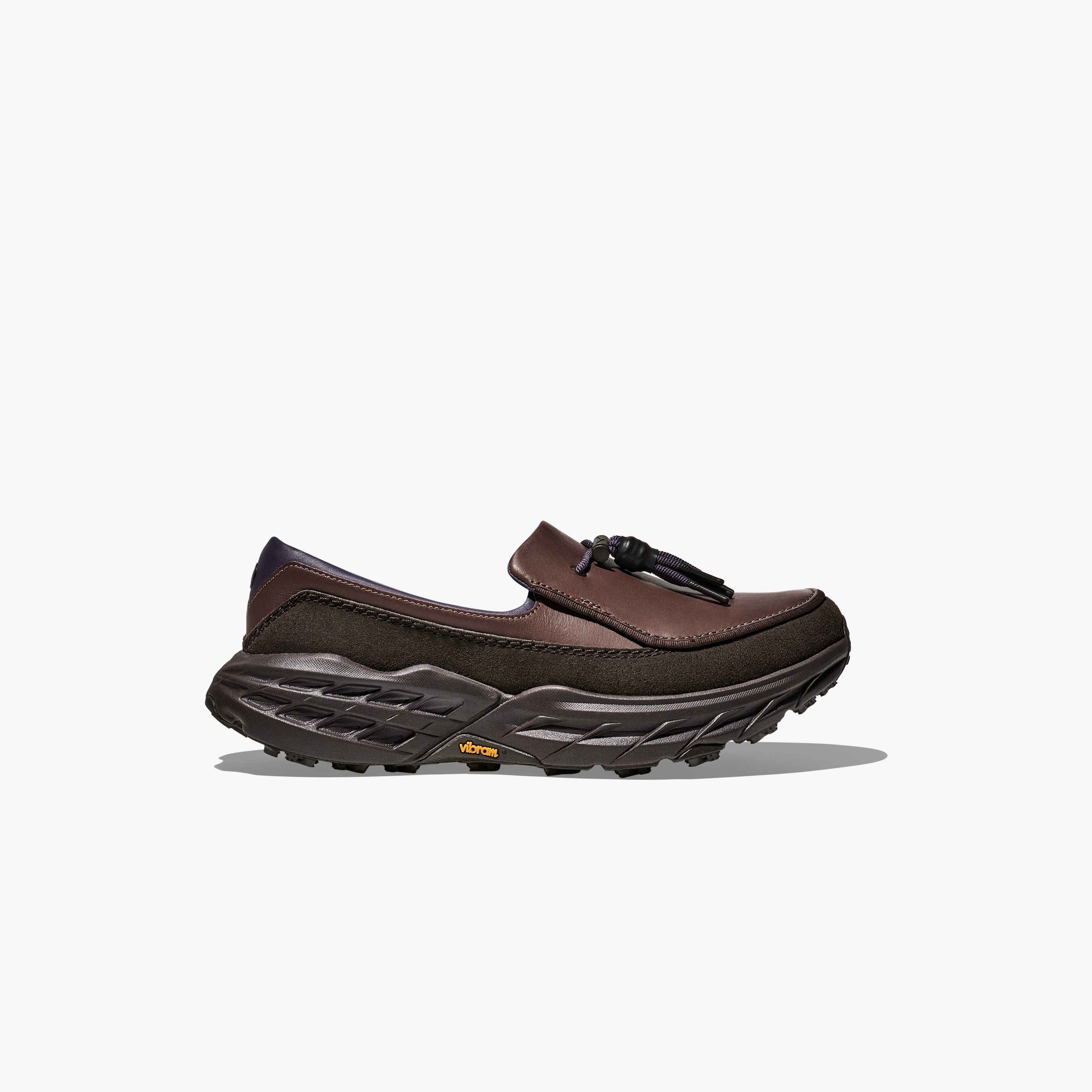 The Hoka U Speed Loafer features brown leather and suede, a chunky black treaded sole, and tassel detail, shown in profile against a plain white background.