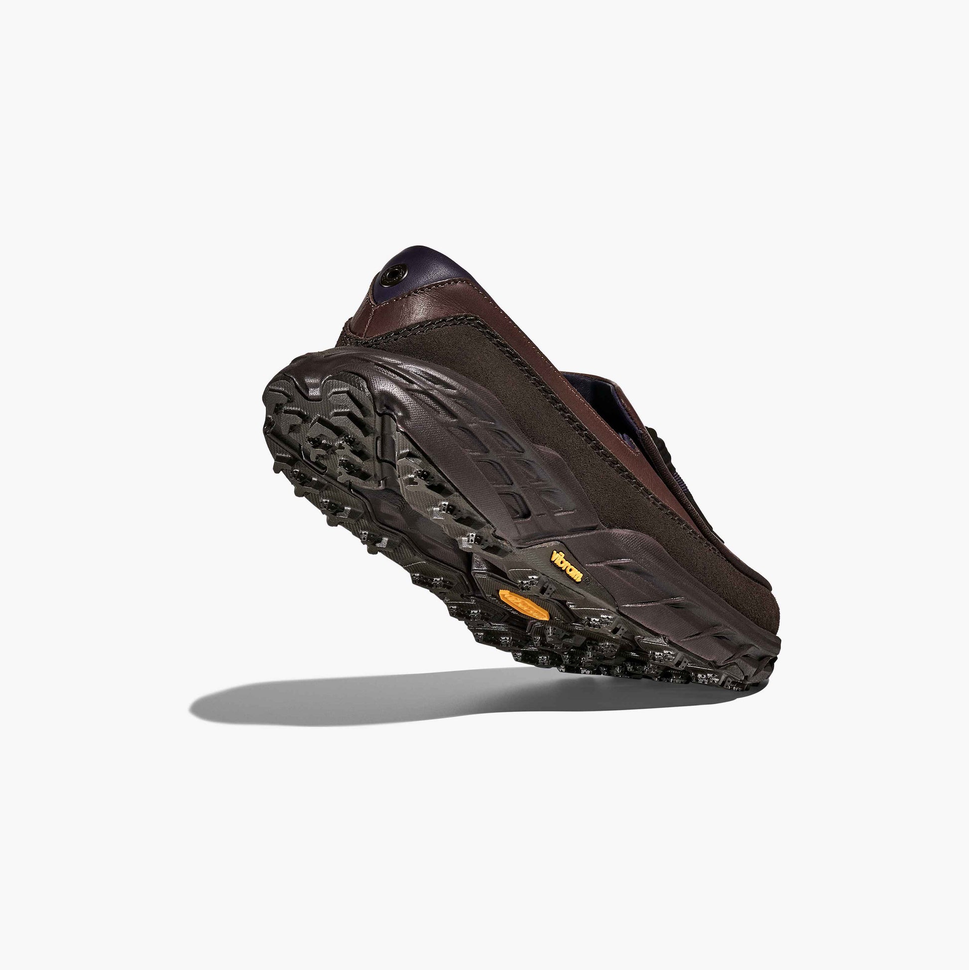 A rear view of the Hoka U Speed Loafer in brown, highlighting its textured black and yellow sole with signature Hoka tread, set against a plain white background.