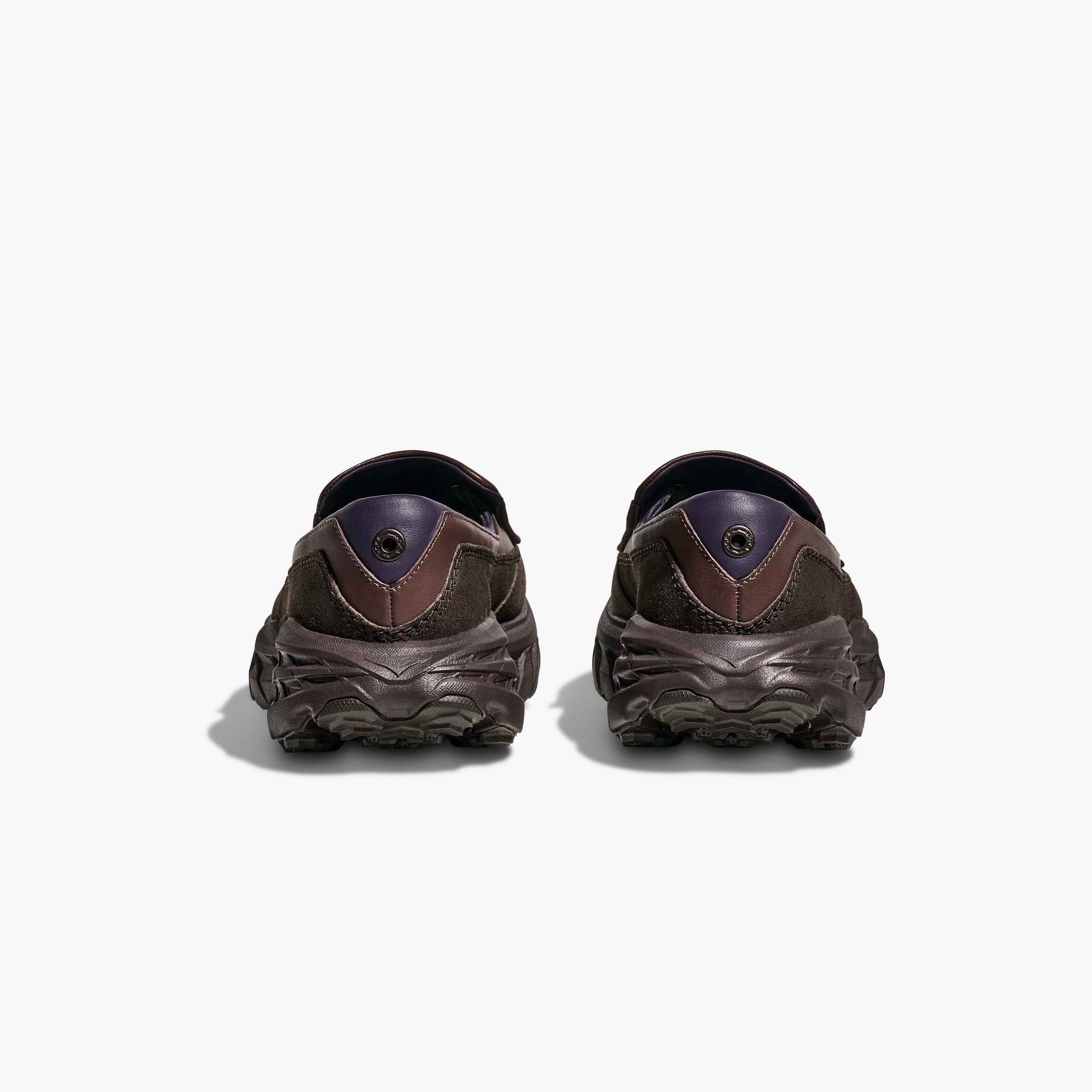 A pair of Hoka U Speed Loafer slip-on shoes in brown leather and suede, shown from the back against a plain white background, highlighting signature Hoka comfort.