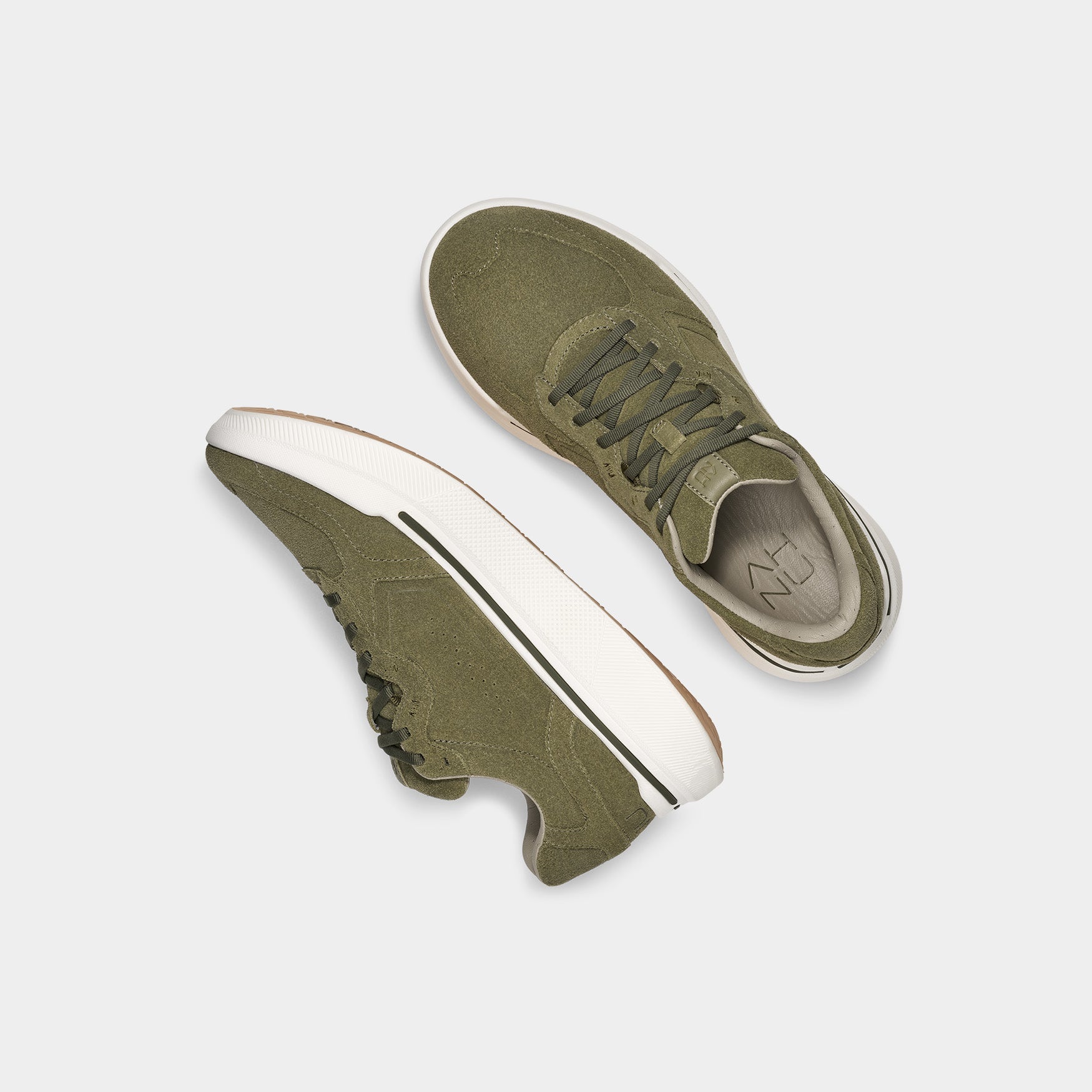 A pair of AHNU M Sequence 1.1 Suede sneakers in olive green are displayed on a plain white background, with one upright and the other showing its sole, highlighting the premium foam padding for ultimate comfort.