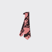 The Kardo Tie, Coral Block Print, is displayed flat on a white background and showcases a striking black base with bold red abstract patterns.