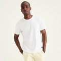 A man stands against a light background with his hands in his pockets, wearing the Dockers Men's Crewneck Tee and light-colored pants.