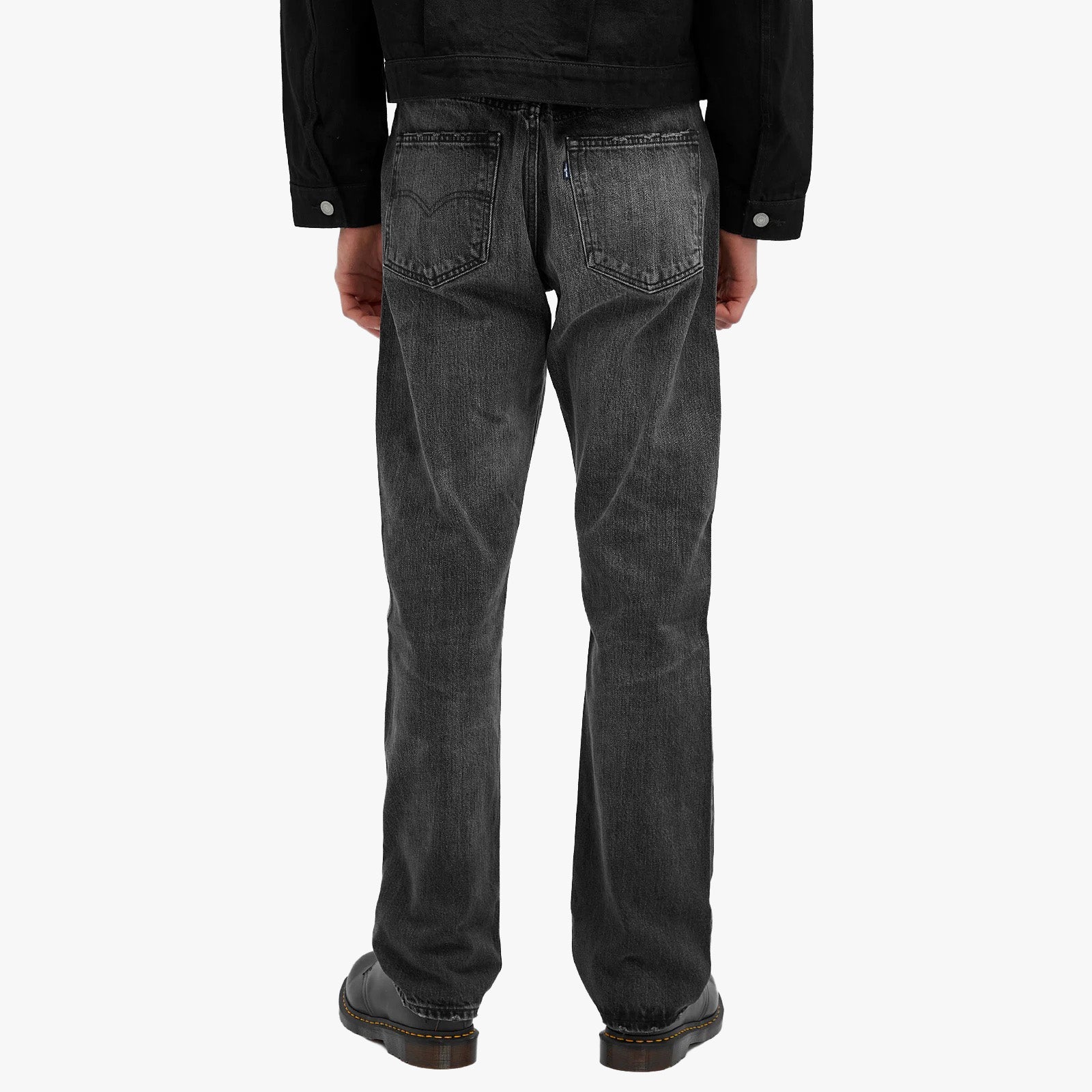 Model is seen from the back wearing Levis 505 MIJ Texas Tea black denim jacket and faded black straight-leg jeans with black shoes, set against a plain white background.