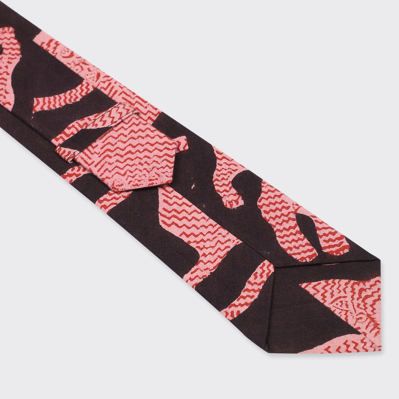 A close-up of the Kardo Tie, Coral Block Print, featuring a black base with abstract red and pink wavy patterns.