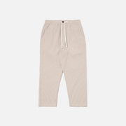 The Ospina Check Cotton High Water Trouser in Ecru/Sand by Universal Works features a button closure, elastic waistband, side pockets, and straight leg fit, shown laid flat on a white background.