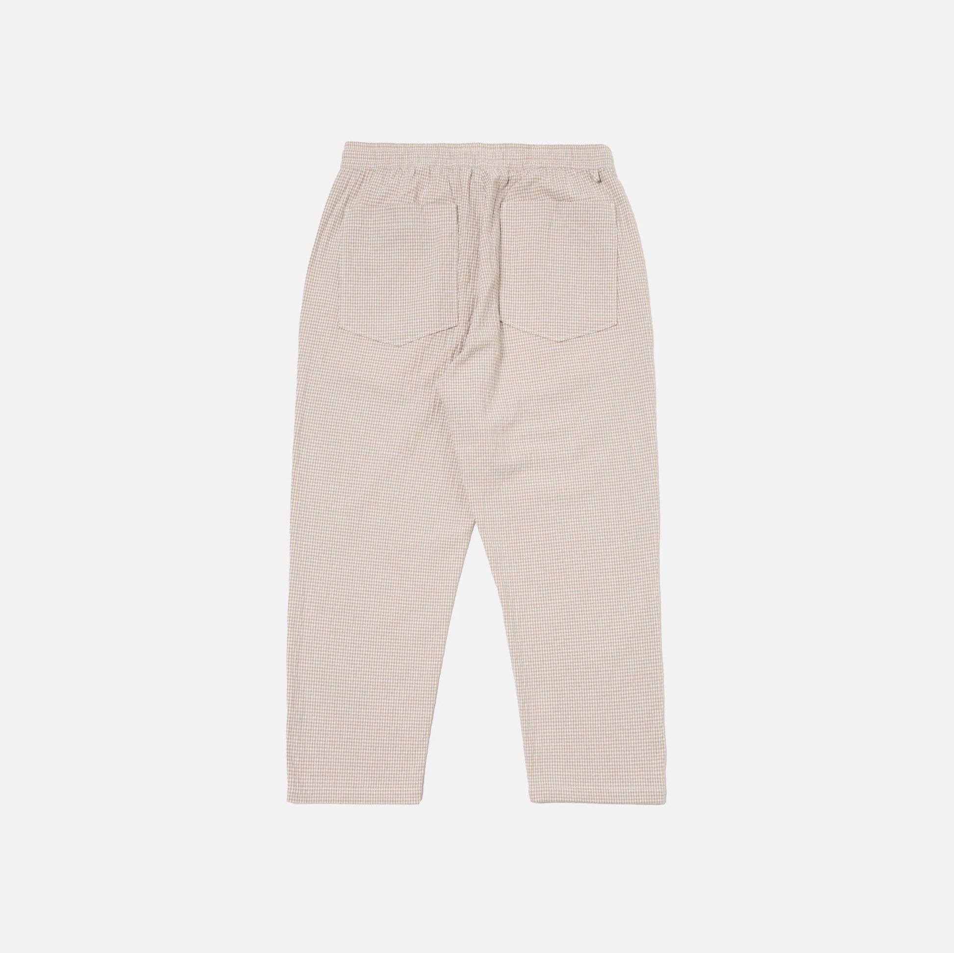 The Universal Works Ospina Check Cotton High Water Trouser in Ecru/Sand is shown flat from the back, highlighting its textured fabric, elastic waistband, and two rear patch pockets.