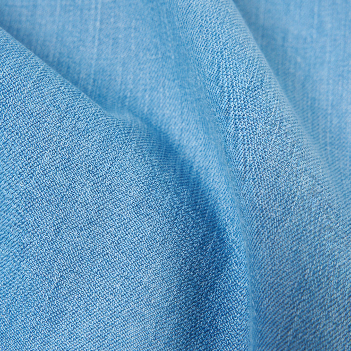 Close-up view of 8 Oz Organic Denim Military Chino in Washed Indigo by Universal Works, highlighting its light blue texture and weave pattern.