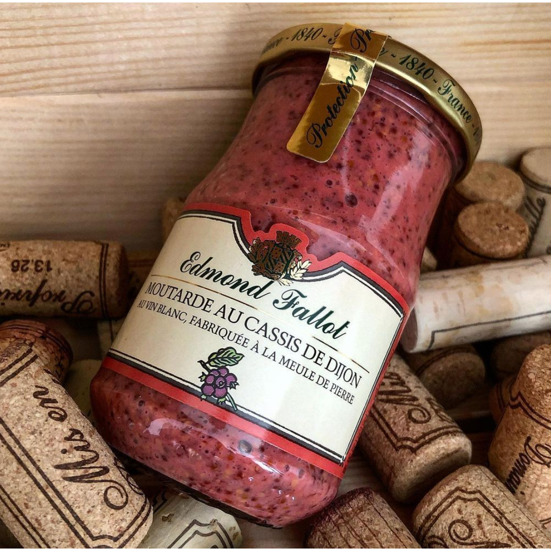 A jar of Edmund Fallot Dijon Mustards, labeled "Moutarde aux Cassis de Dijon," rests amidst several corks.
