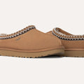 Close-up of Ugg's W's Tasman brown slip-on slippers, featuring an ultra-lightweight design, braided trim, rubber soles, and the UGG logo. They offer ultimate comfort with plush UGGplush™ lining.