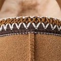 A close-up of the Ugg W's Tasman reveals intricate brown, white, and gold stitching near the opening, complemented by its ultra-lightweight slip-on design.