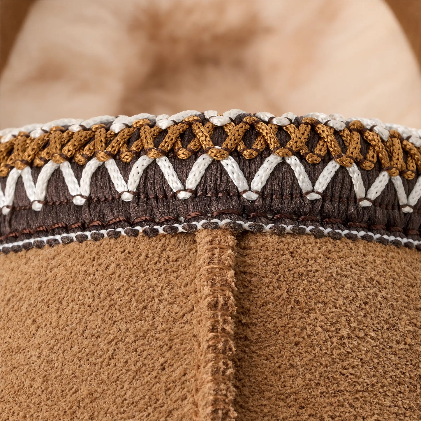 A close-up of the Ugg W's Tasman reveals intricate brown, white, and gold stitching near the opening, complemented by its ultra-lightweight slip-on design.