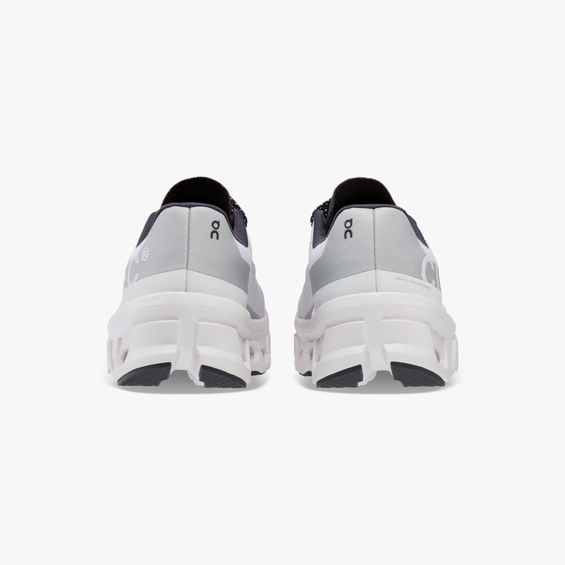 Rear view of a pair of On Running M Cloudmonster sneakers in All White, featuring thick soles with Helion™ superfoam, positioned side by side against a plain white background.