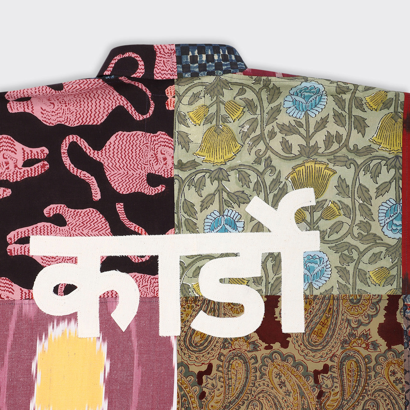 The Fanette Overshirt, Patchwork 07 by Kardo from the SS25 collection features a mix of floral and abstract fabrics, overlaid with bold white Devanagari script.