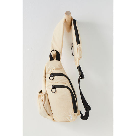 A Renegade Sling in Ivory with adjustable crossbody strap hanging on a wooden mannequin against a white wall.