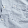 Close-up of the Dockers Men's Signature Shirt, LS in light blue, made from Mechanical Stretch Poplin with a chest pocket and a small embroidered logo above it.