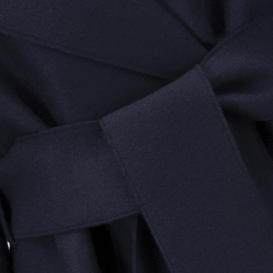 Close-up of a dark navy W Belted Clutch Coat in pressed wool by Harris Wharf, featuring a smooth belt tied in a knot with overlapping layers.