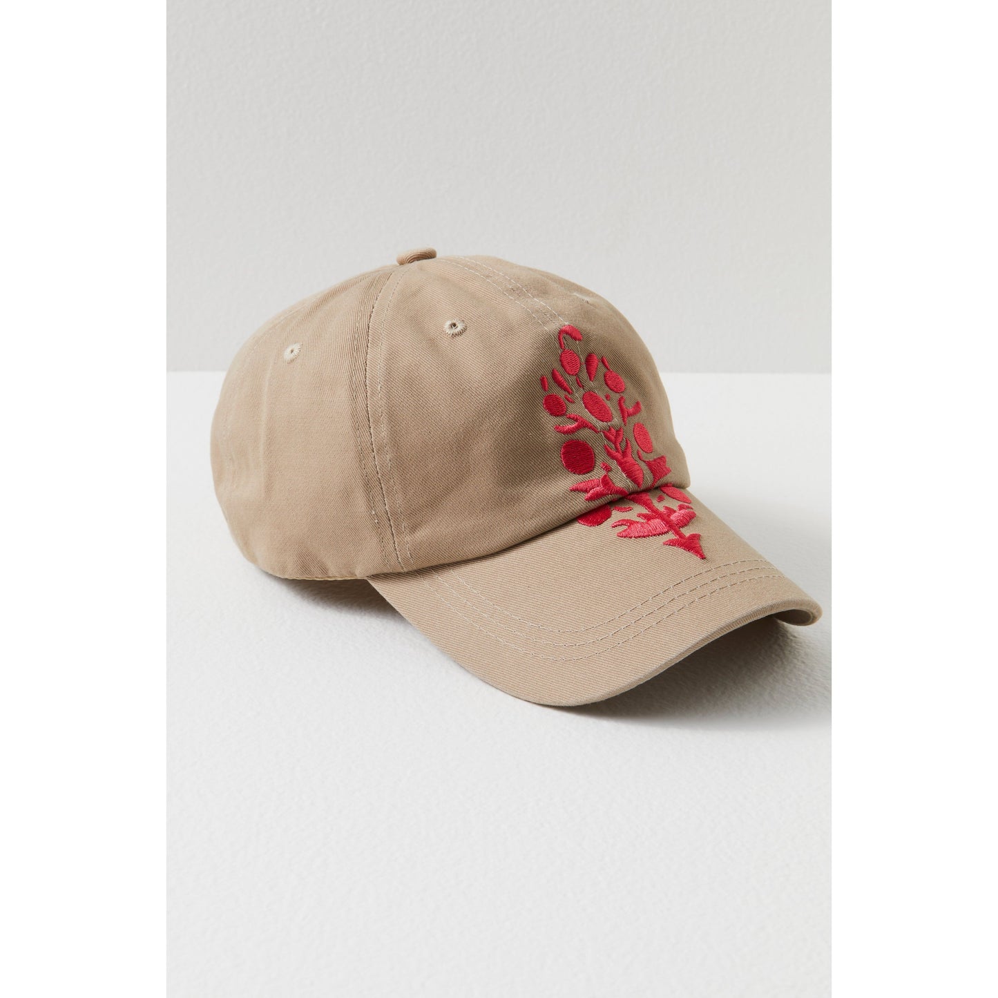 A Sand/Coral Big Buti baseball cap with red floral embroidery on the left side, displayed on a white surface by Free People Movement.
